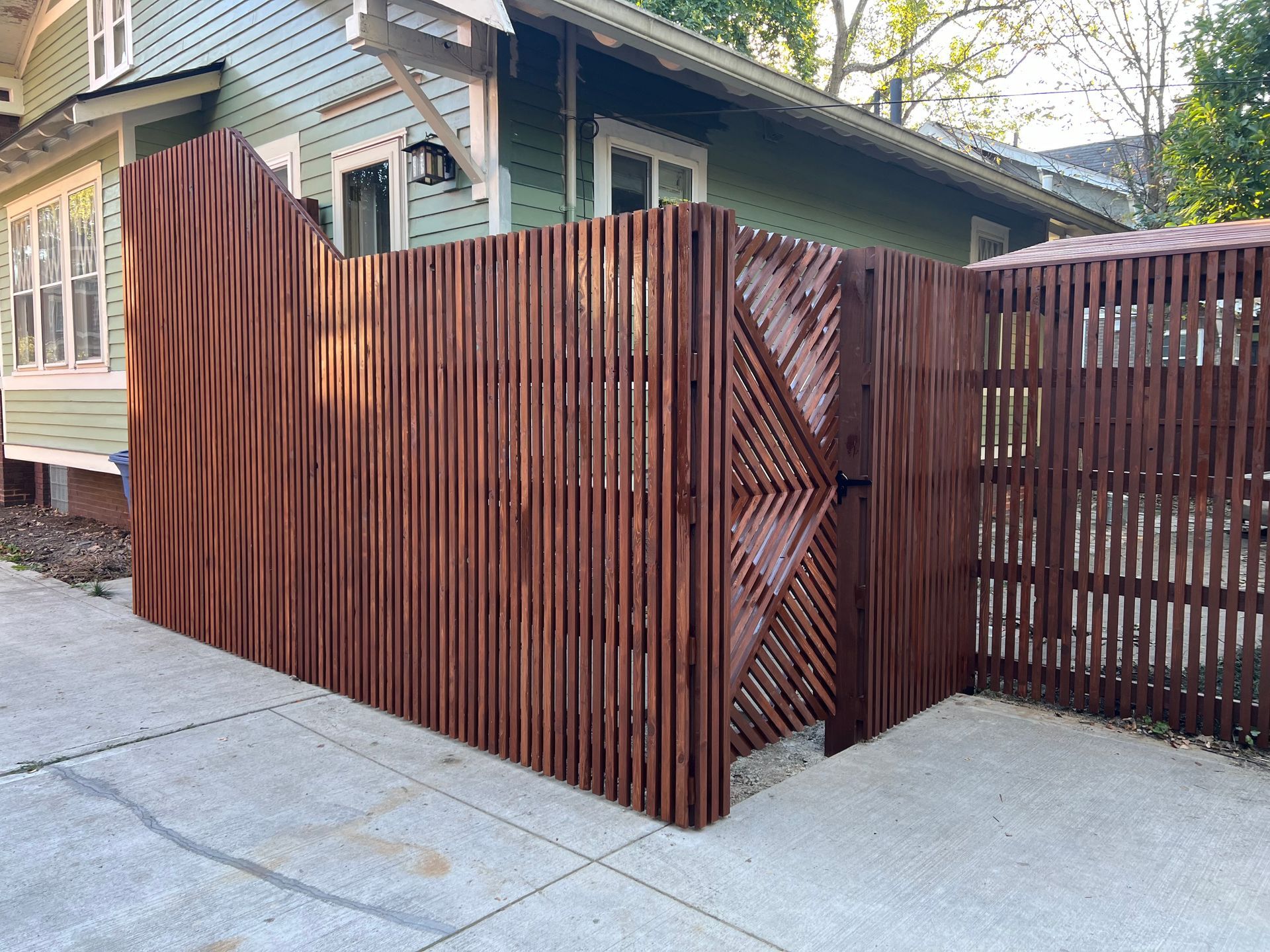 A wooden fence with a gate in front of a house.