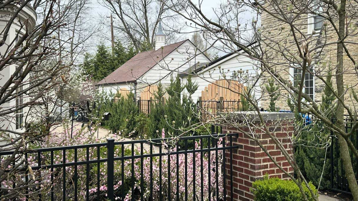 A black fence surrounds a brick wall in front of a house.