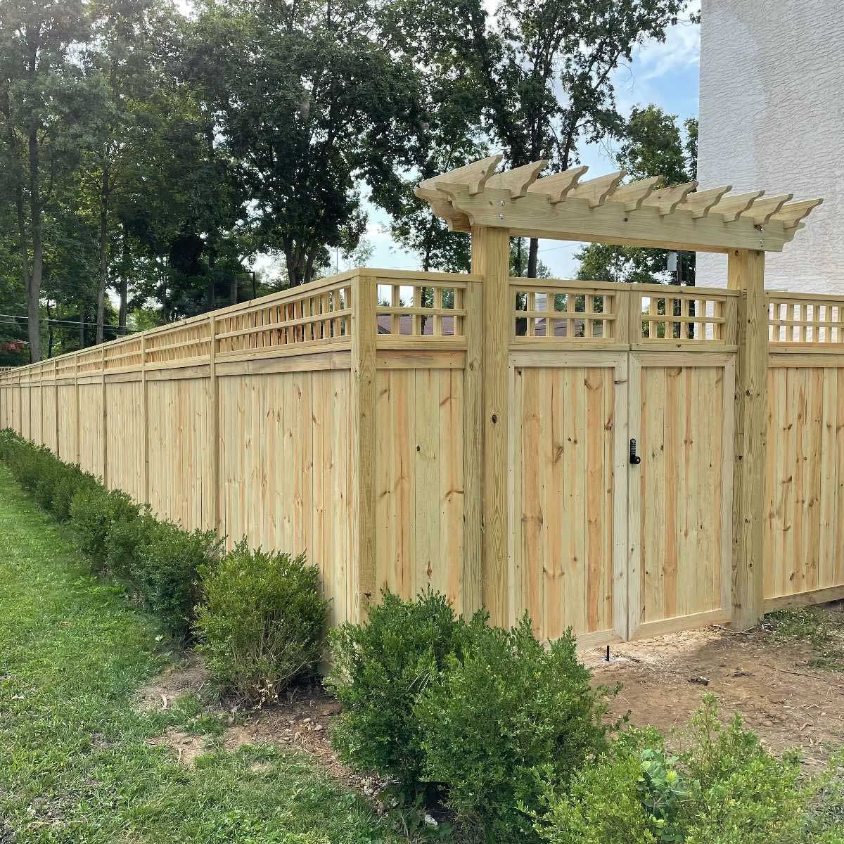 A wooden fence with a gate and a pergola on top of it.