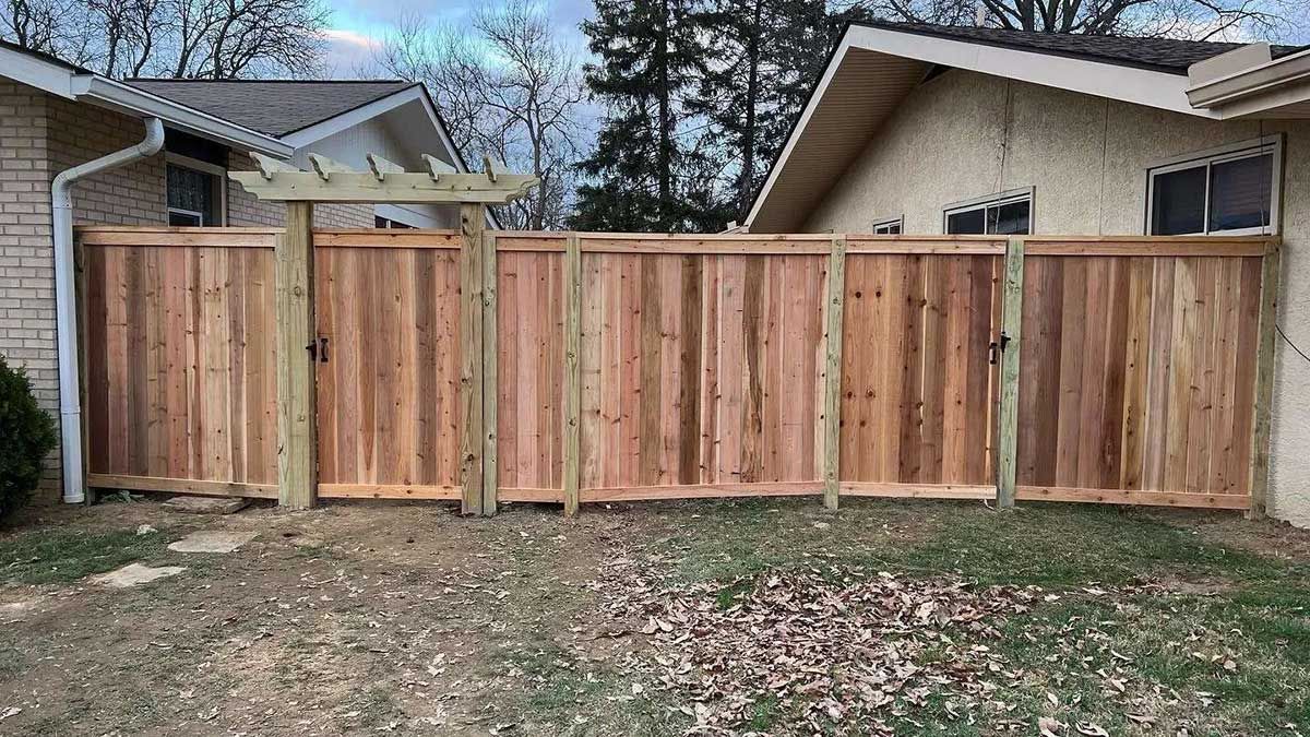 A wooden fence with a gate in front of a house.