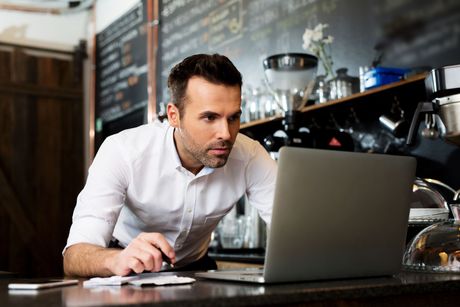 A man is sitting at a counter using a laptop computer.