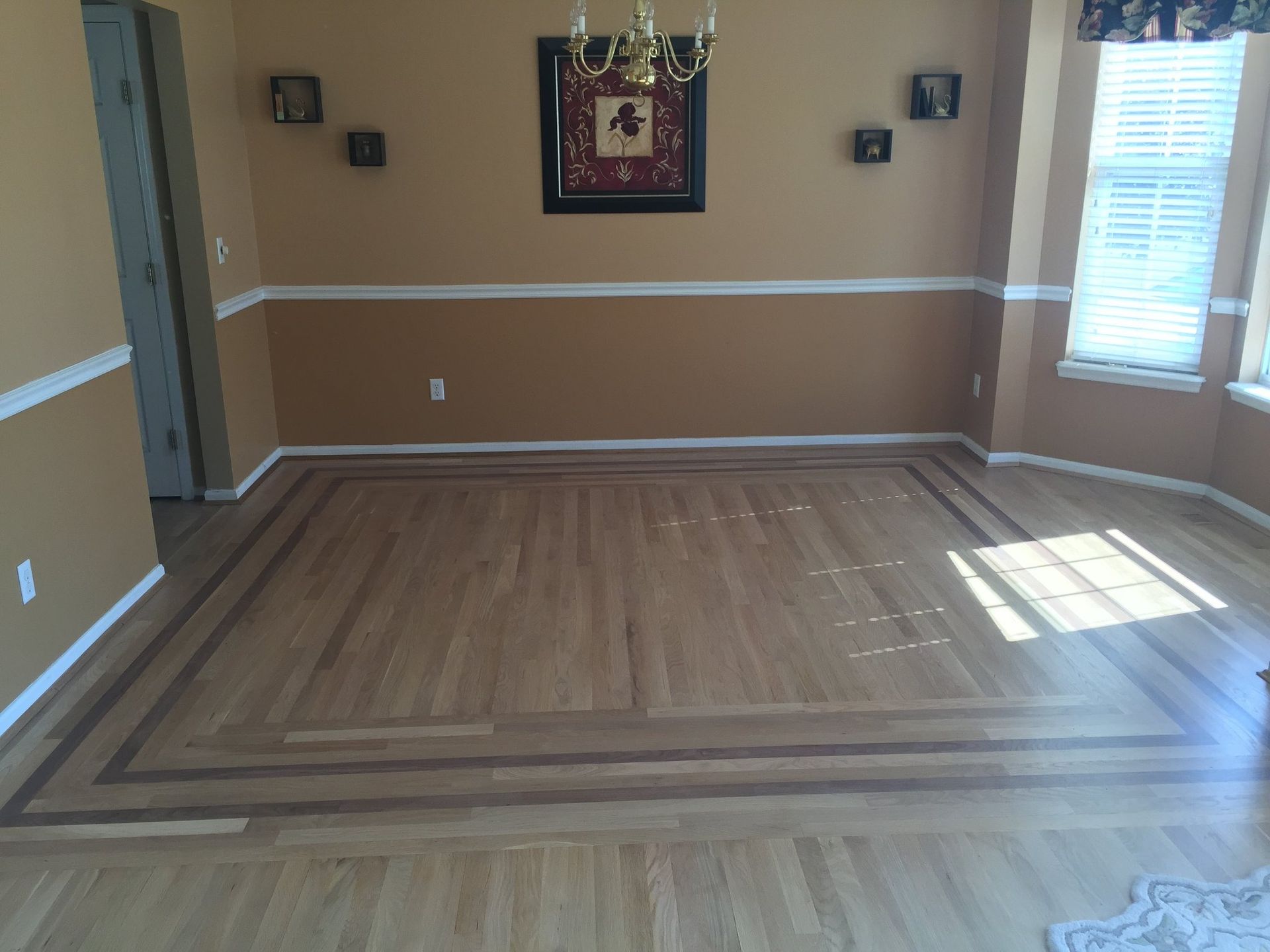 A dining room with a wooden floor and a picture on the wall