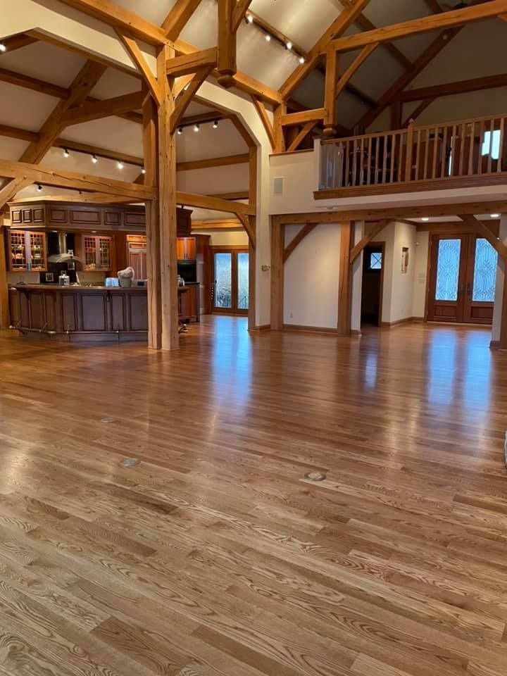 A large empty room with wooden floors and a kitchen.