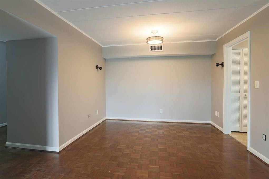 An empty living room with hardwood floors and gray walls