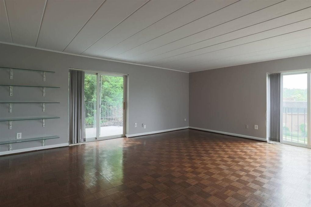 An empty living room with a wooden floor and sliding glass doors.