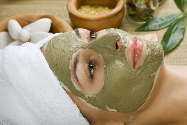 A woman is wearing a green clay mask on her face.