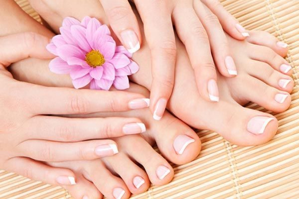 A woman 's hands and feet are holding a pink flower.