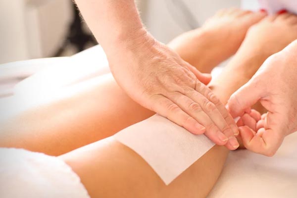 A woman is getting her legs waxed in a beauty salon.