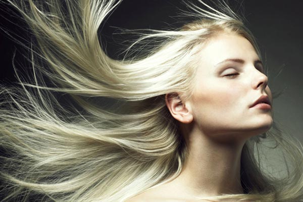 A woman with long blonde hair is blowing in the wind.