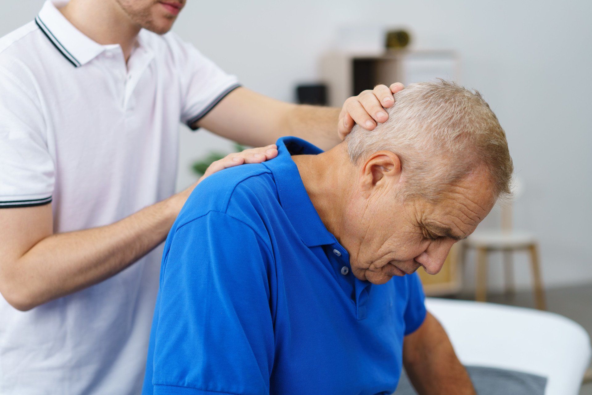 A man is giving an older man a massage on his back.