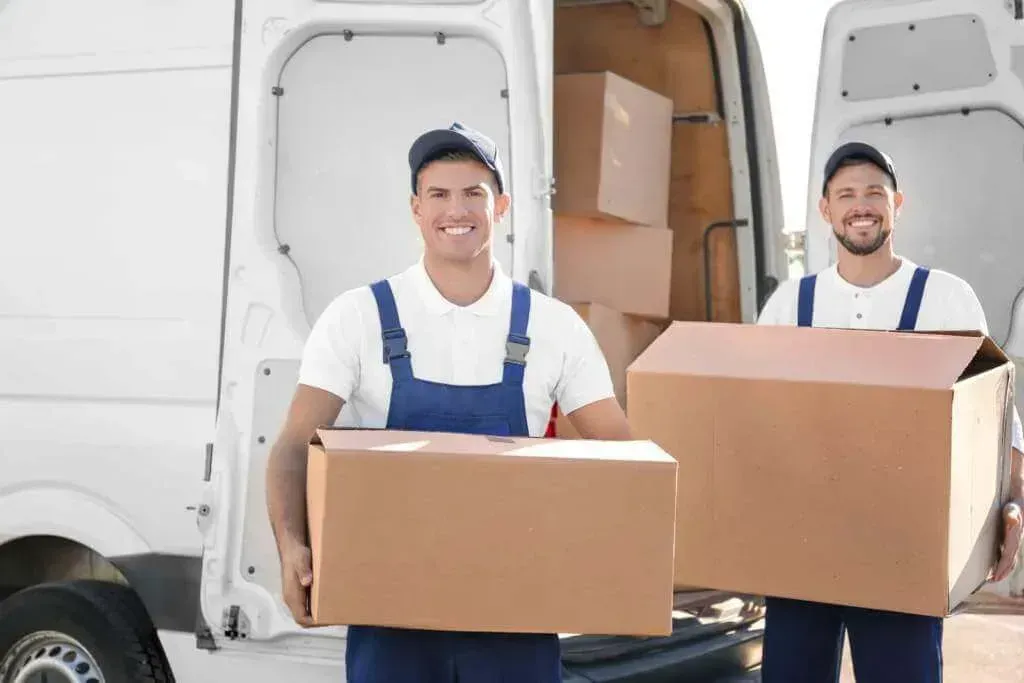 Two movers carrying cardboard boxes from a white moving truck