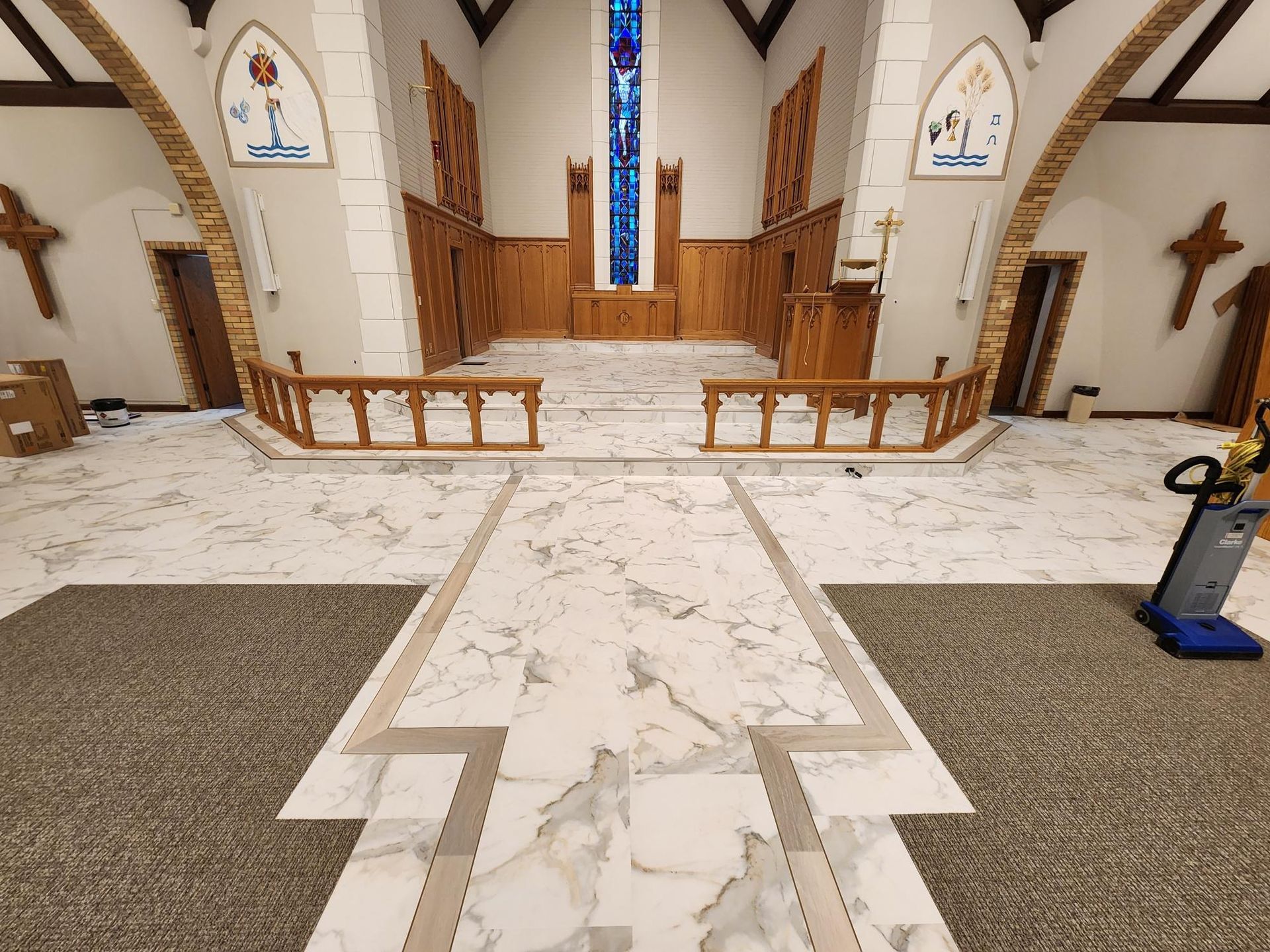 Interior view of a church with marble flooring, wooden accents, and stained glass windows.