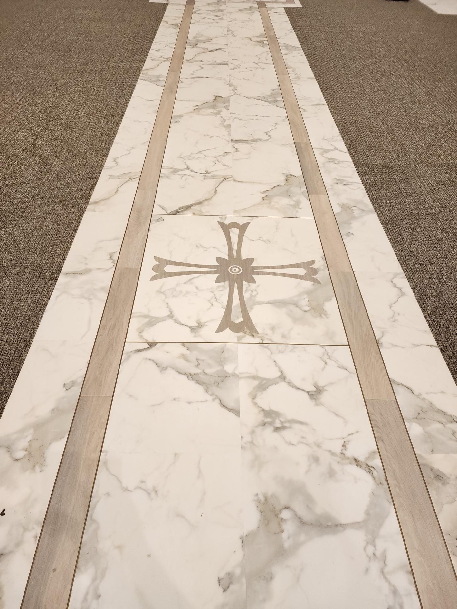 Marble floor pathway with a cross inlay, flanked by gravel sections.