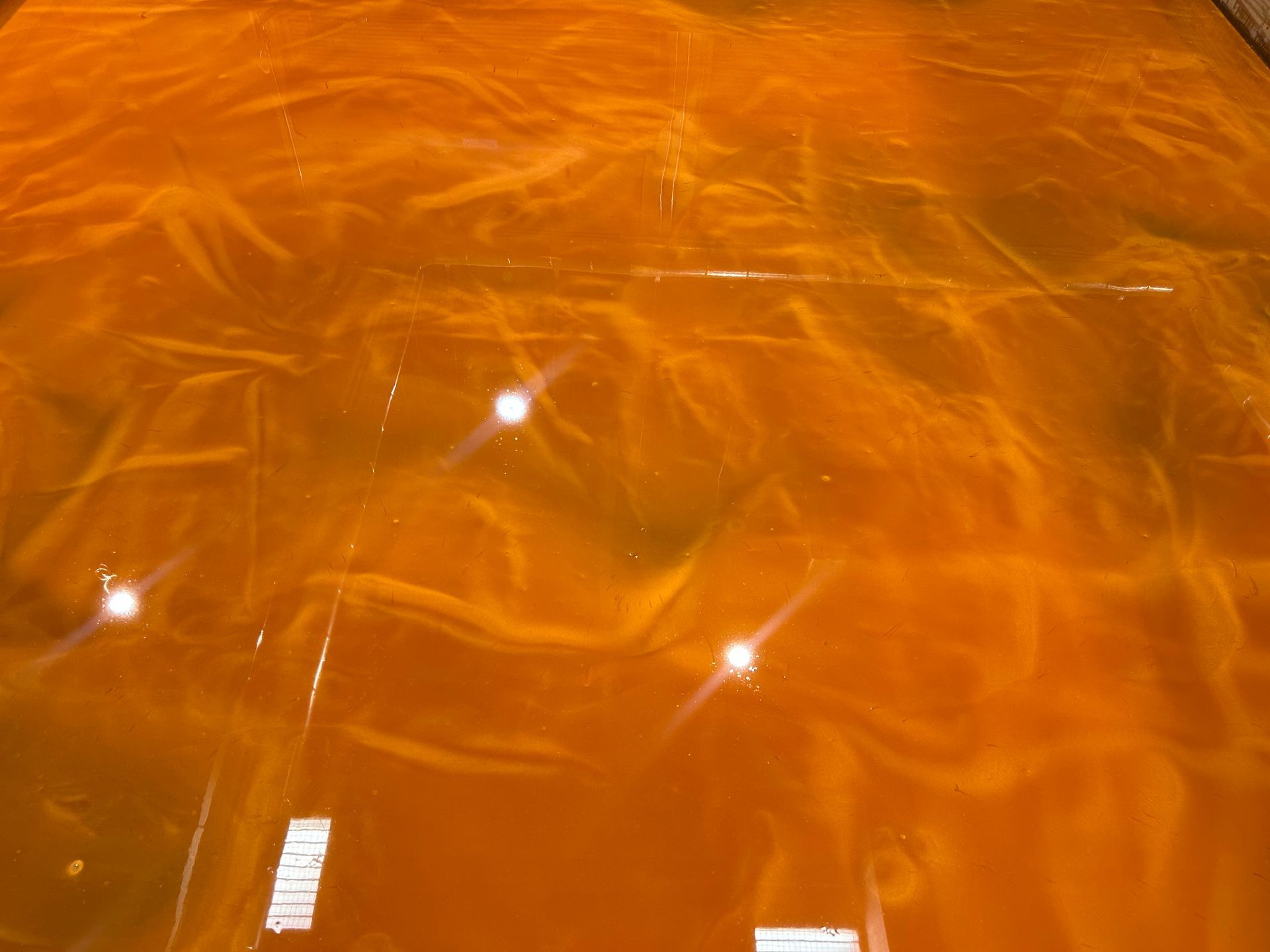 Orange and gold epoxy floor with swirled patterns and reflective highlights.