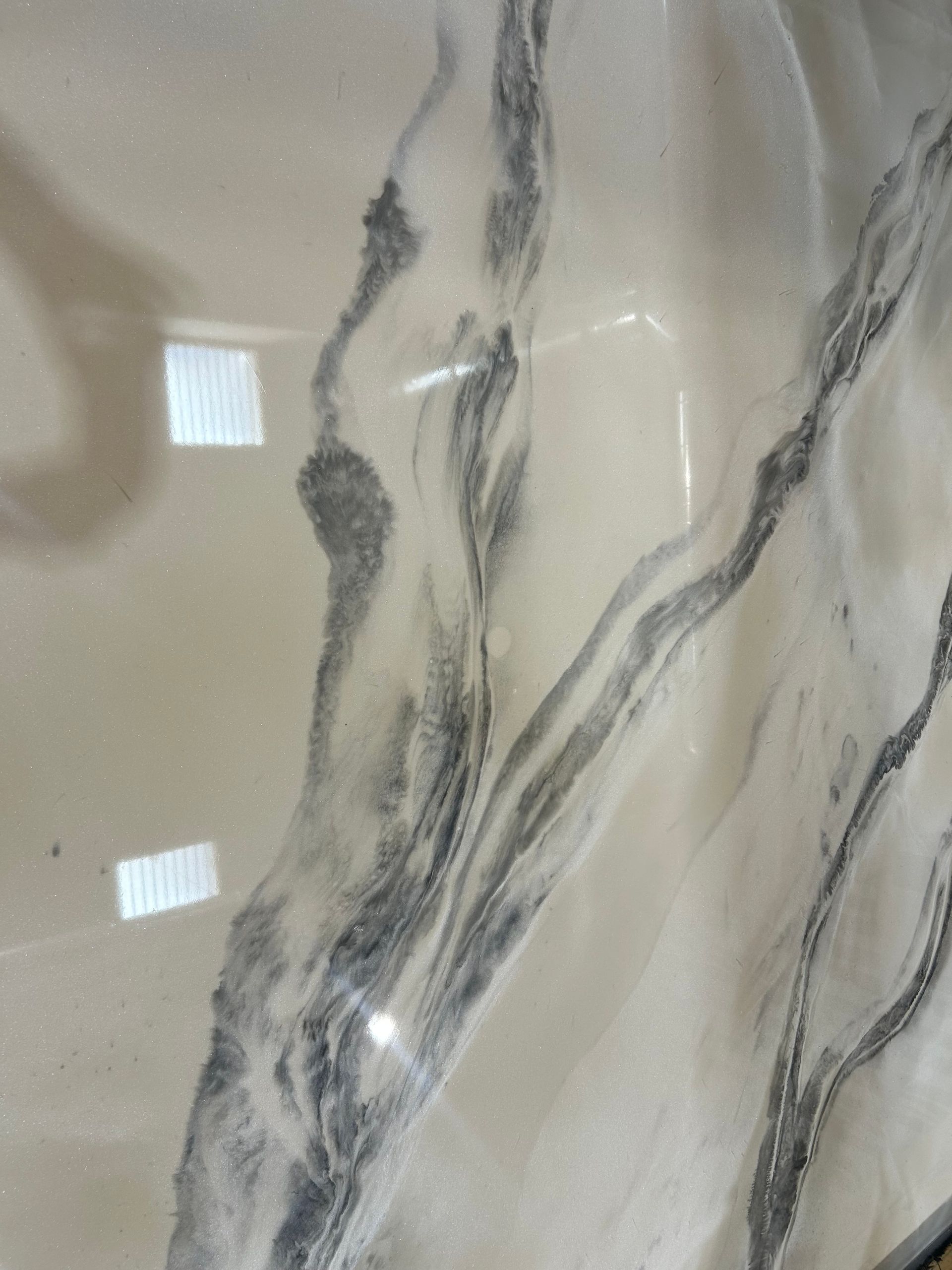 Cream-colored epoxy floor with black and gray marbled veins, reflecting sunlight.