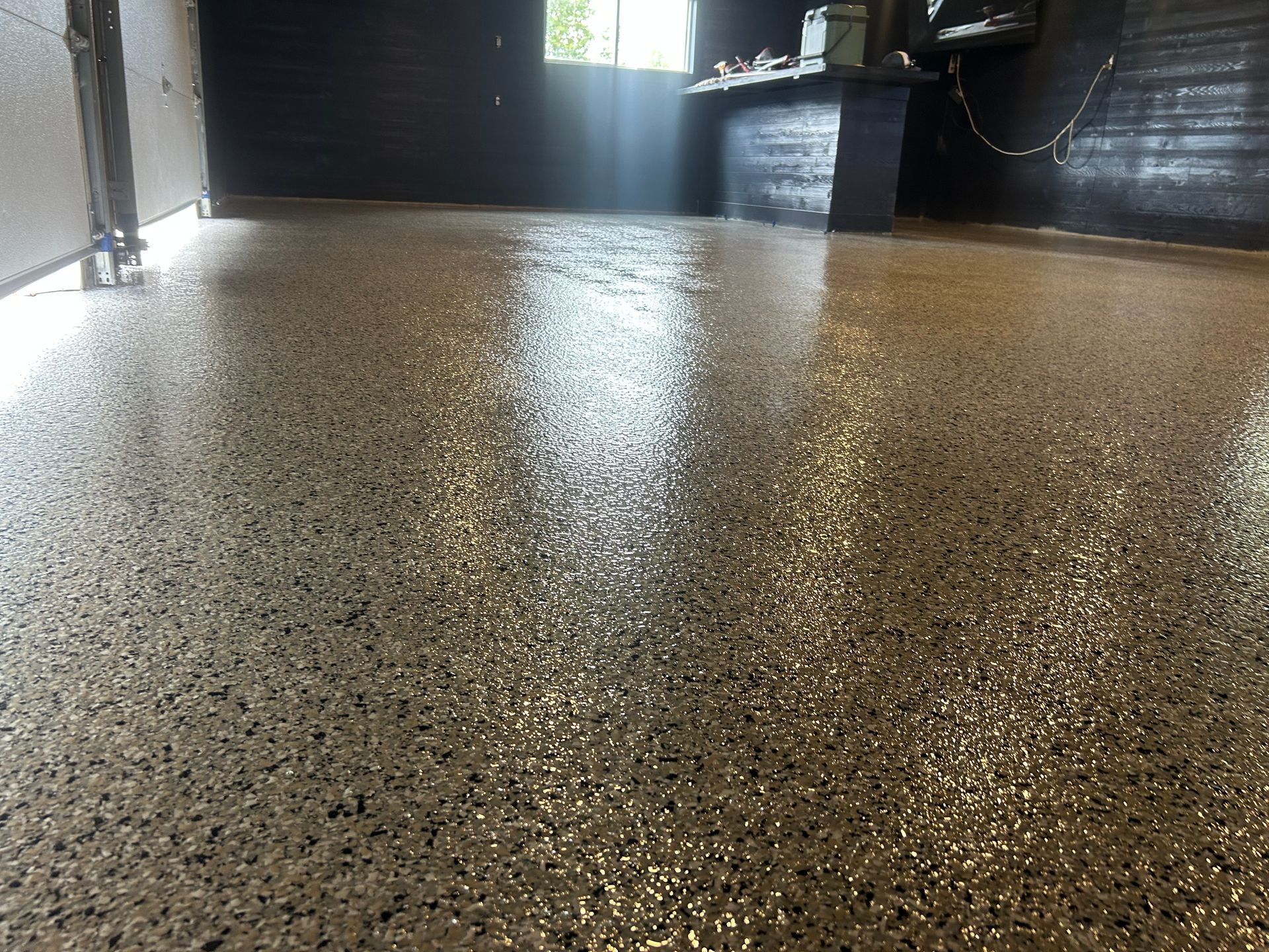 Shiny epoxy floor with speckled gray and black aggregate in a room.