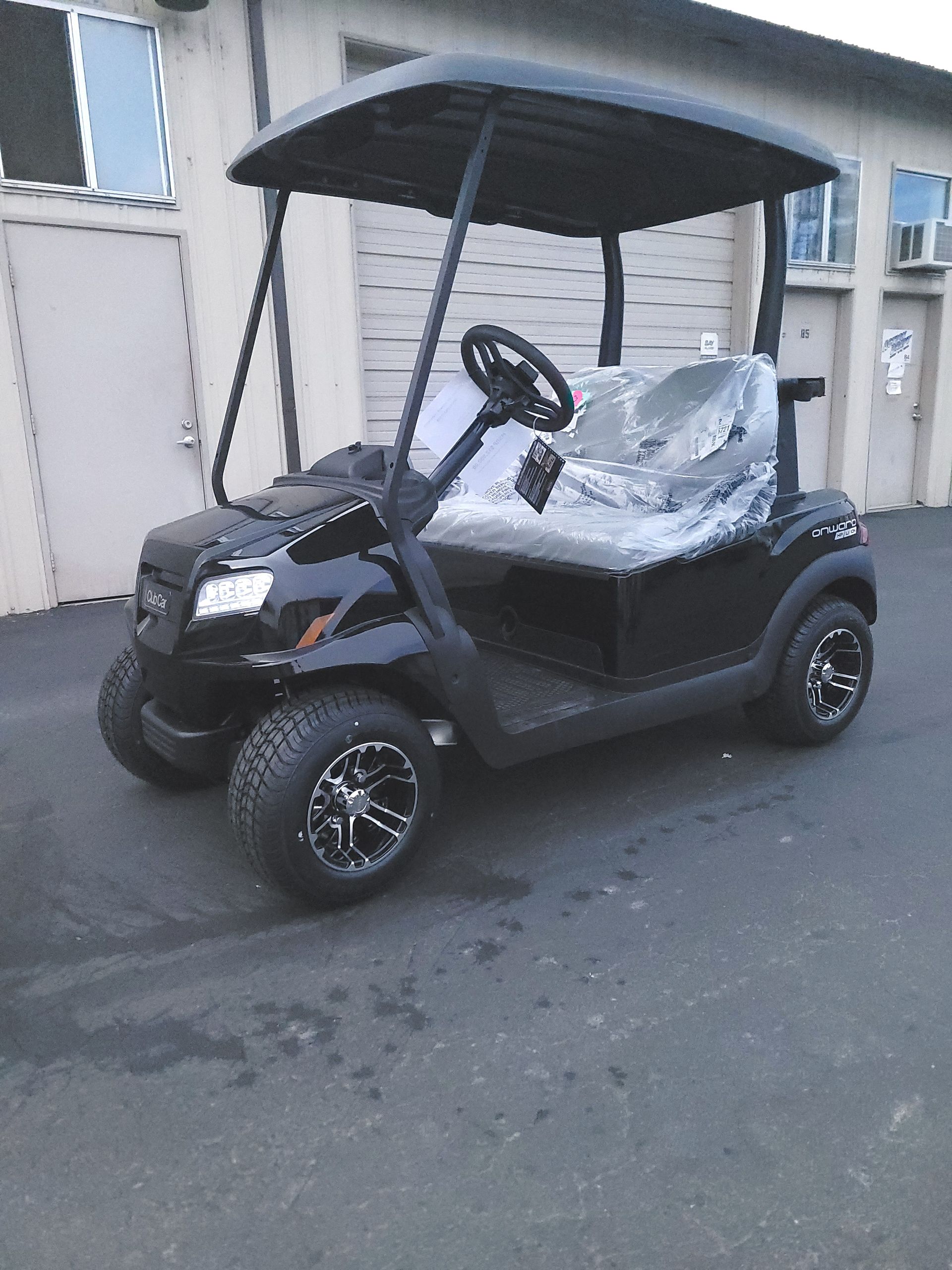 Black golf cart with a canopy parked in front of a building.