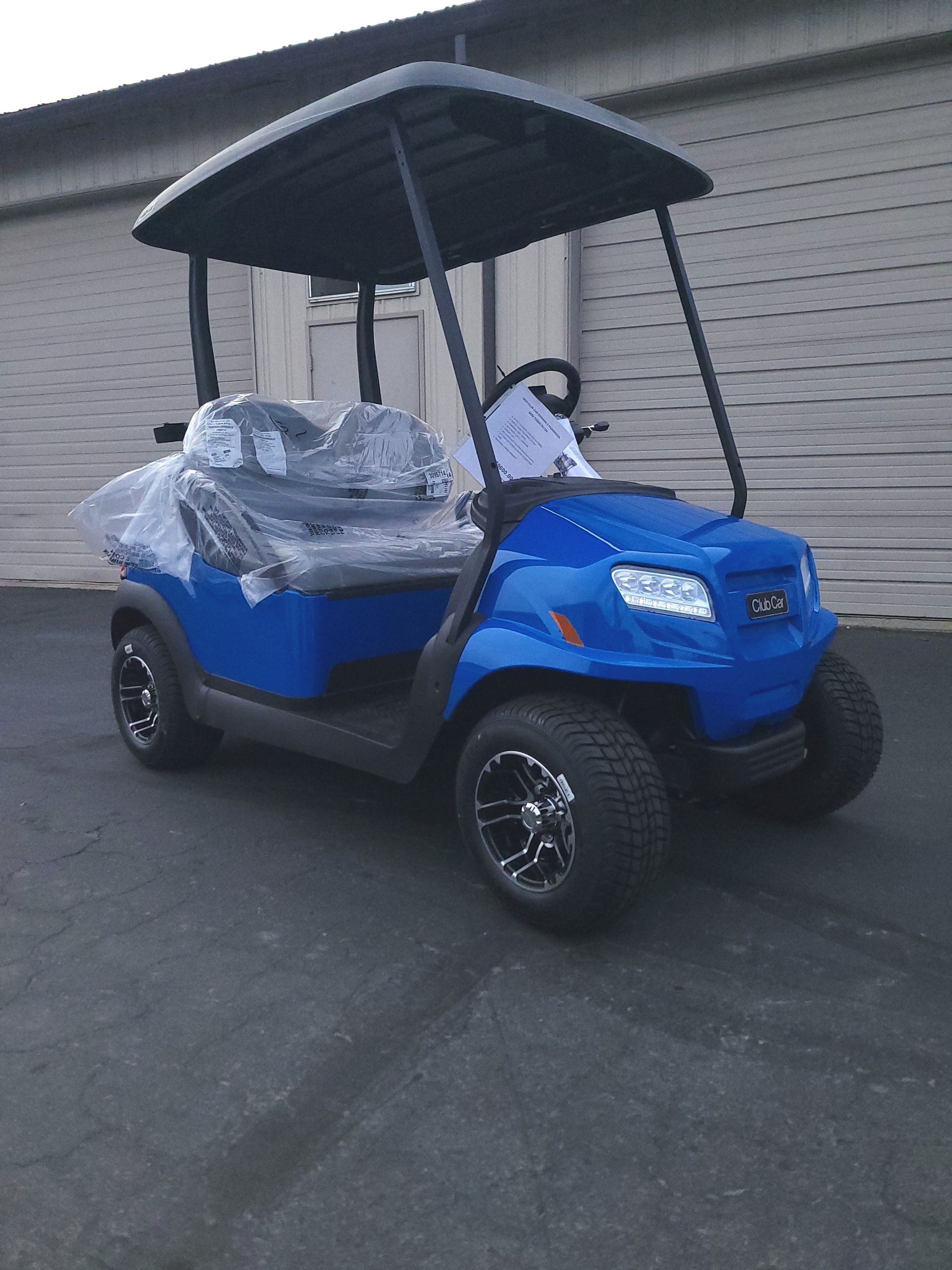 Blue golf cart with a black roof parked on asphalt.