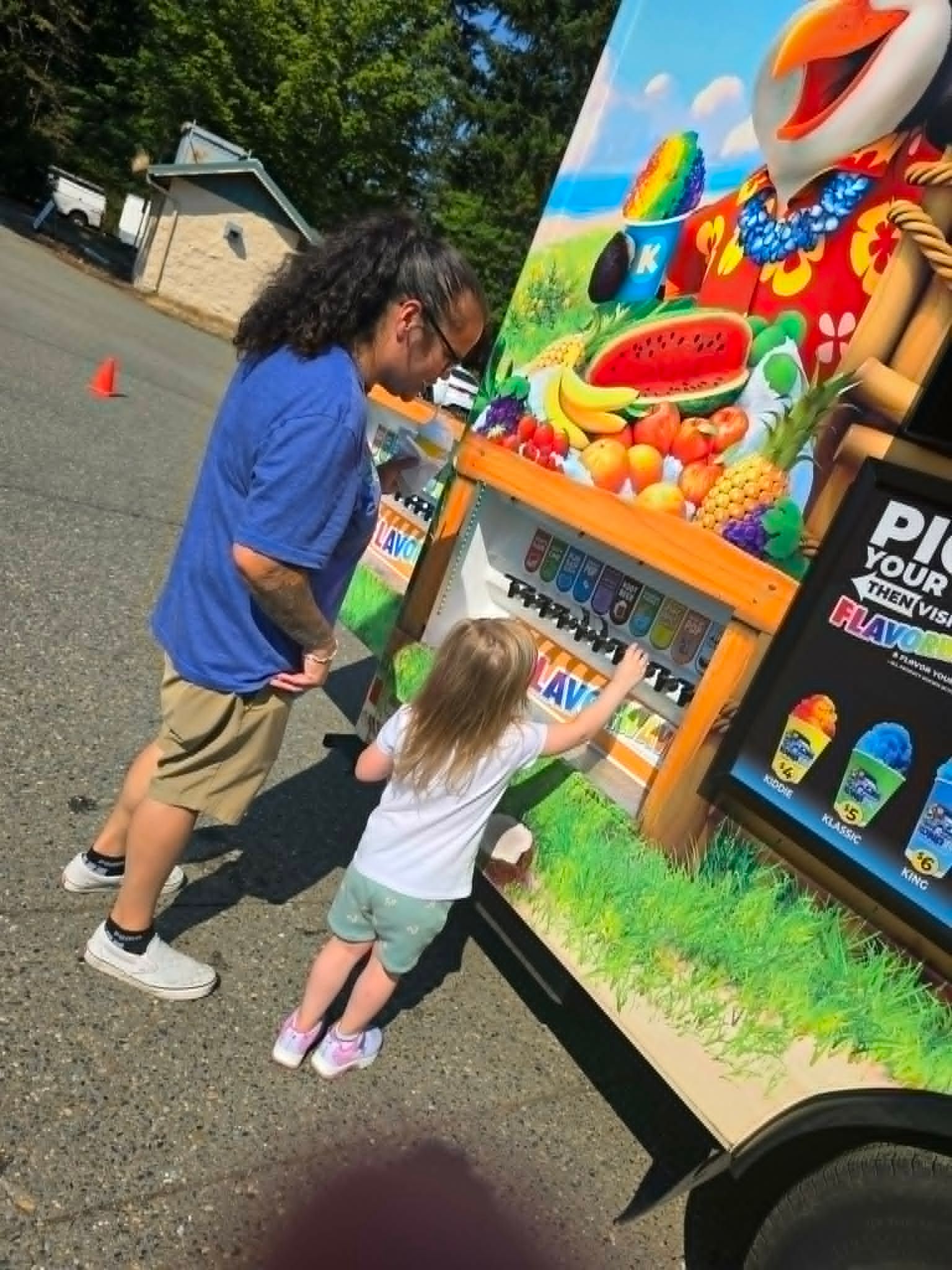 Two children at a colorful amusement game booth, reaching toward a clown-themed prize display.