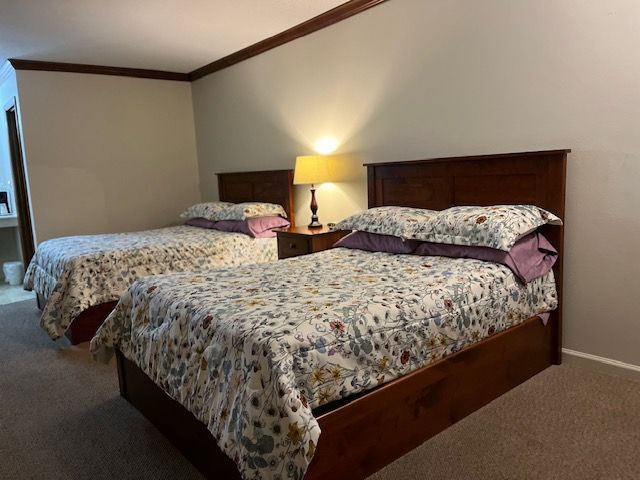 A bedroom with two beds and a lamp