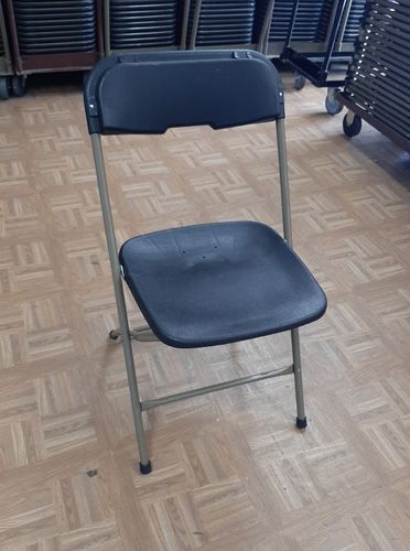 A black folding chair is sitting on a wooden floor.