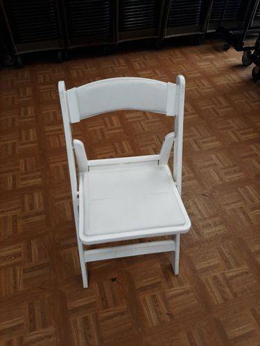 A white folding chair is sitting on a wooden floor.