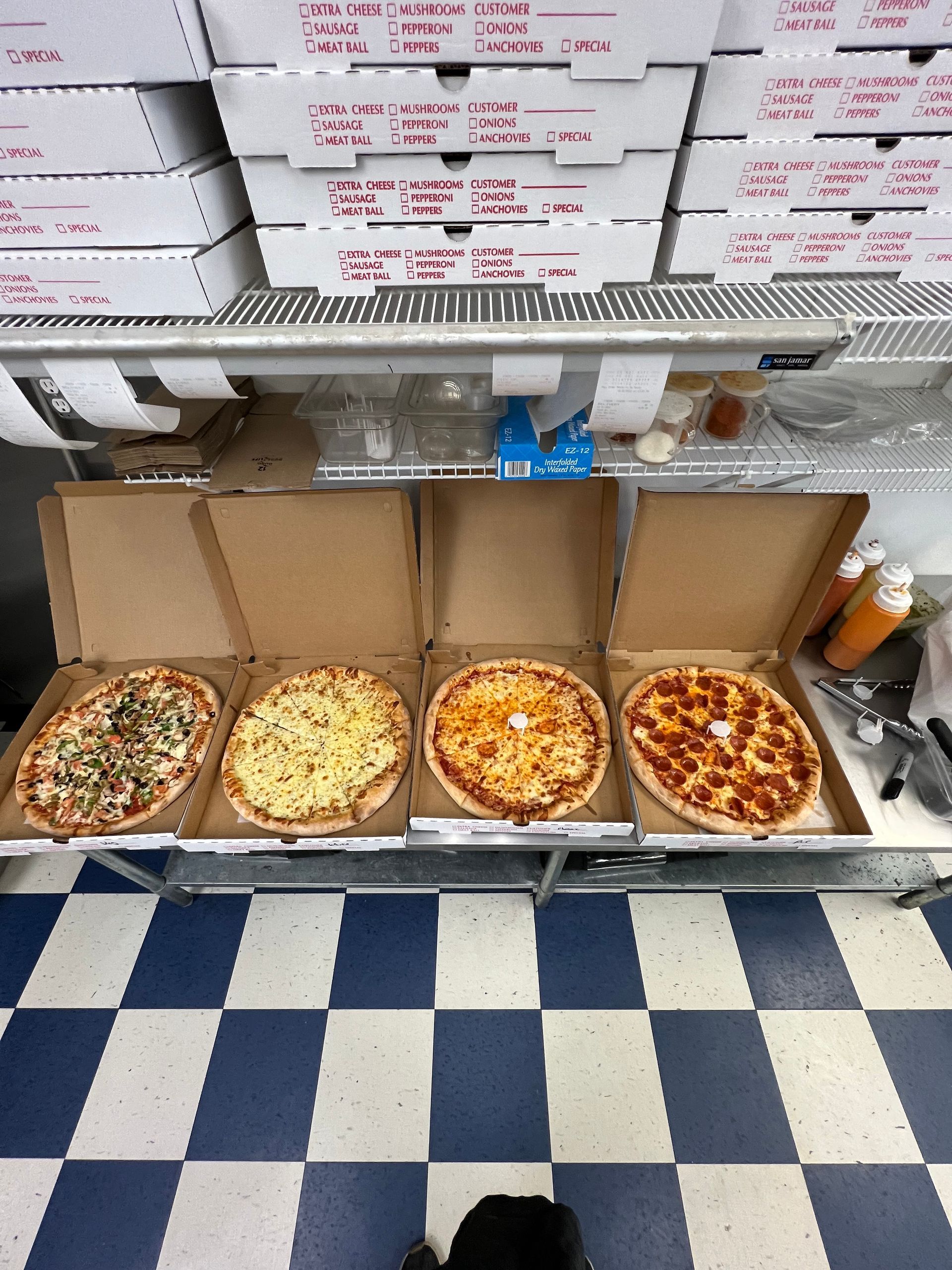 four pizzas in cardboard boxes on a checkered floor
