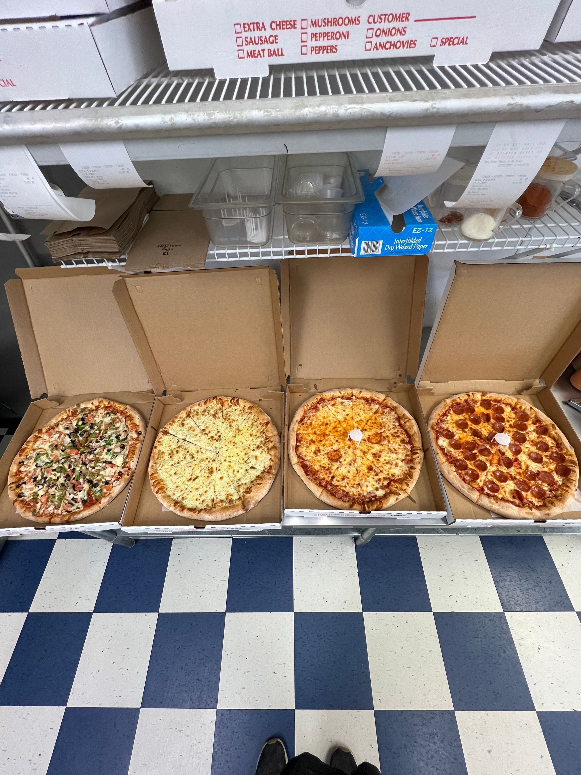 four pizzas are in boxes on a checkered floor