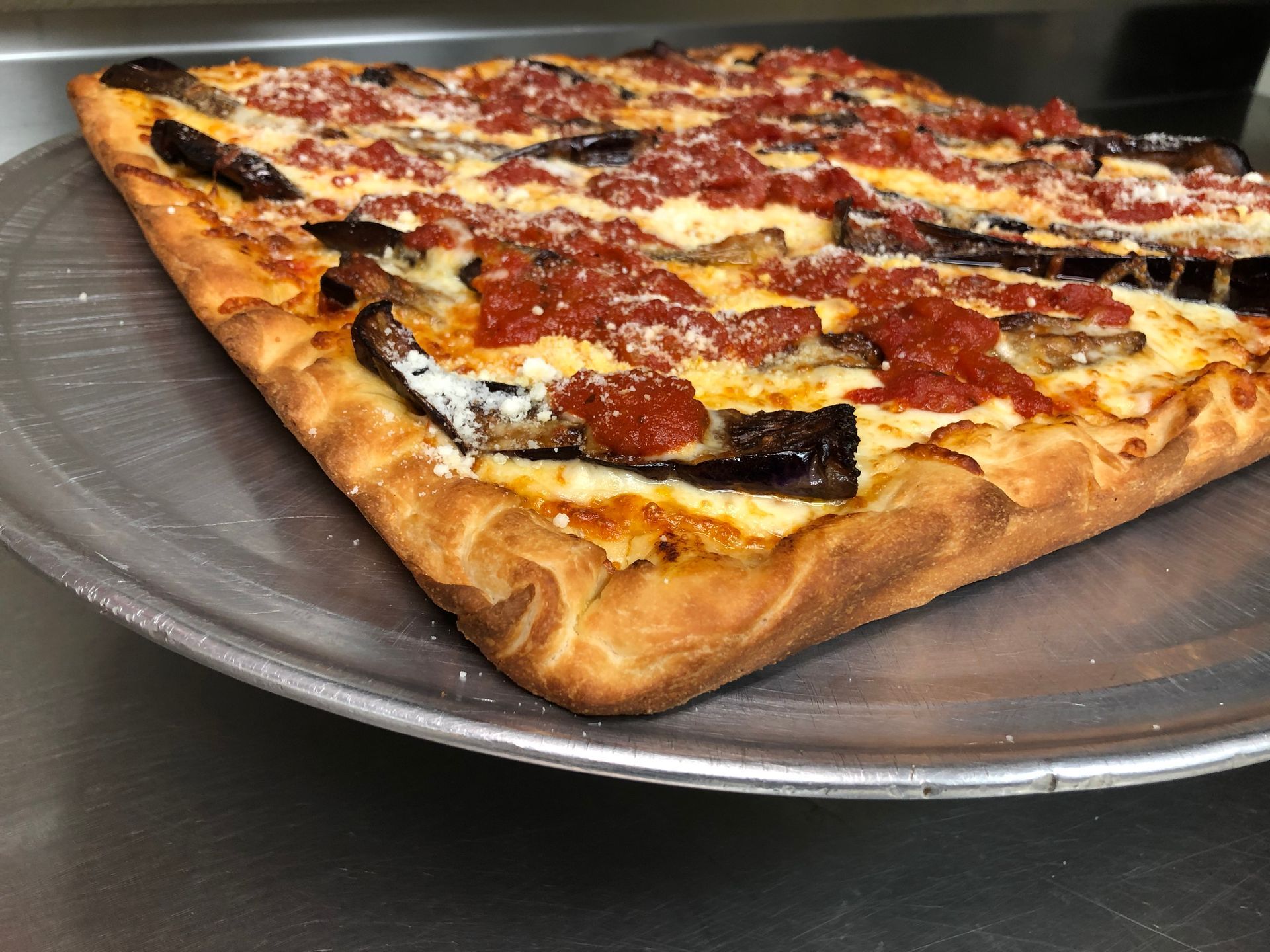 a pizza with eggplant and tomatoes on it is on a pizza pan