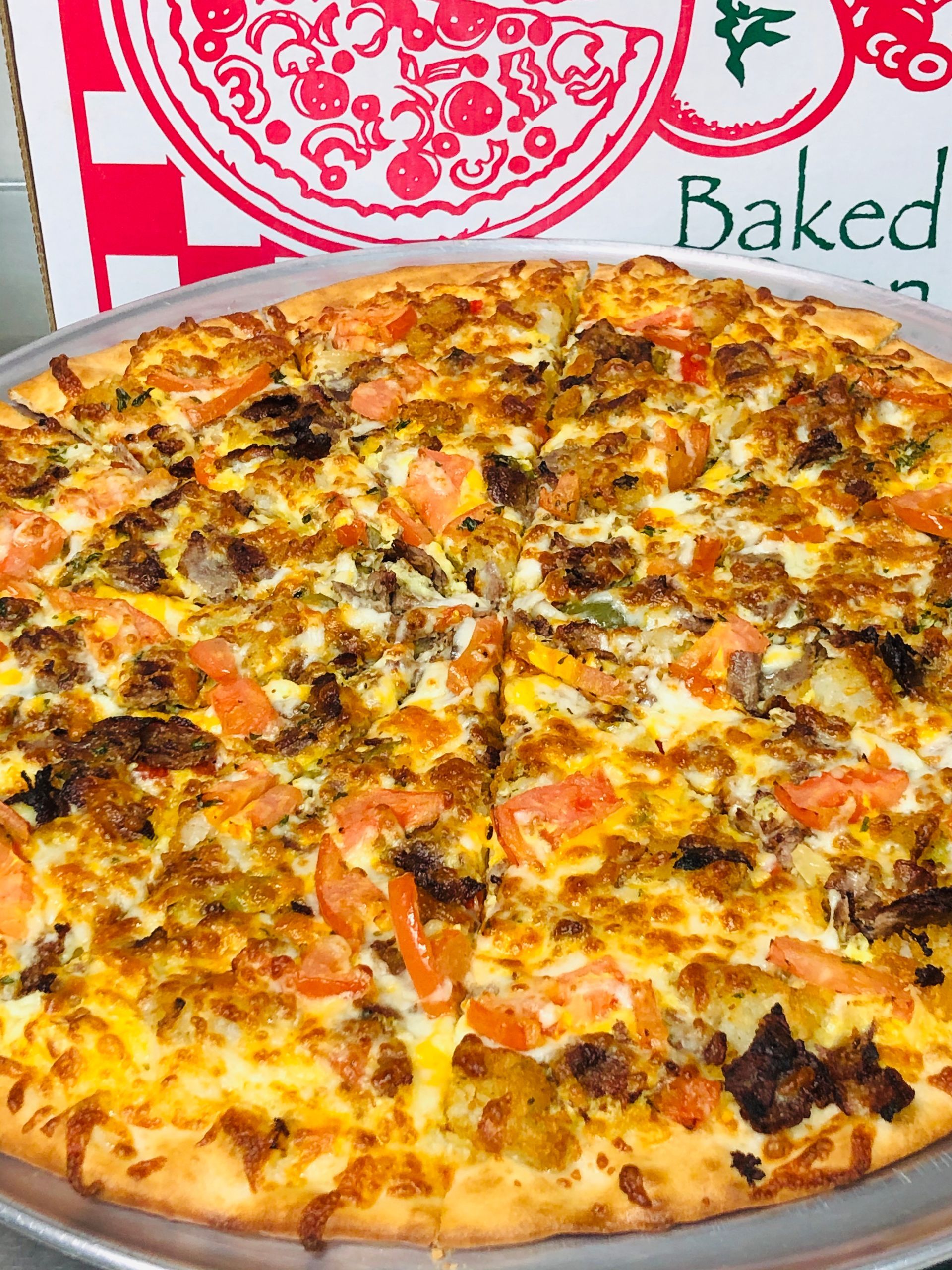 a pizza is sitting on a pan in front of a box that says baked