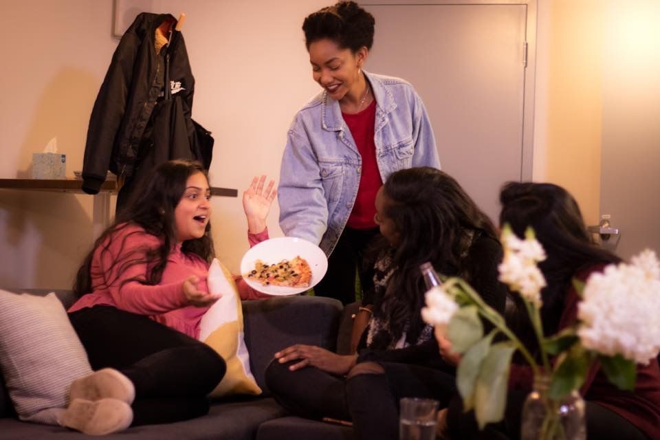 a group of women are sitting on a couch eating pizza