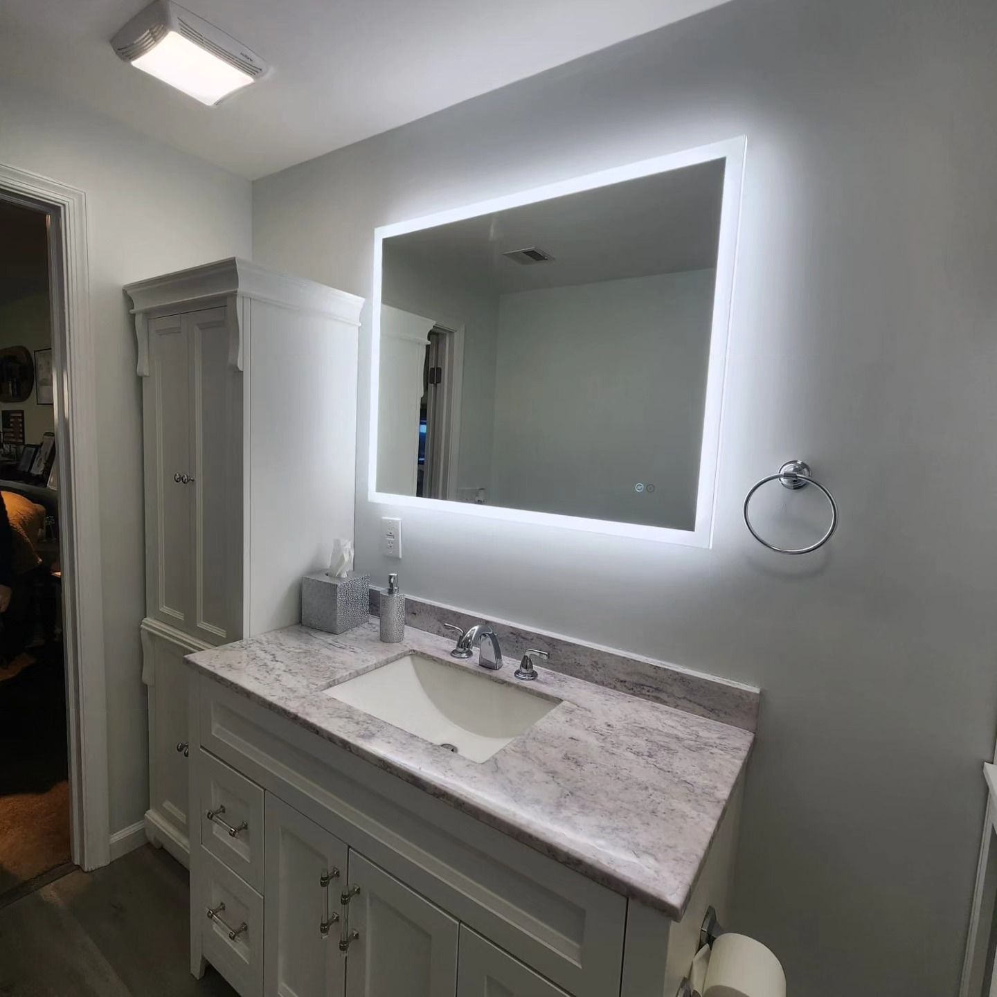 A bathroom with a sink and a mirror with lights on it.