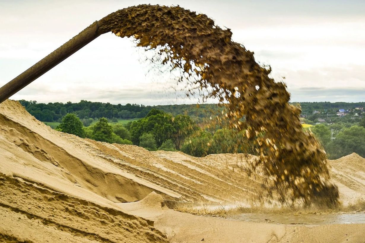 Conveyor belt pouring sand into a large pile at a construction or industrial site