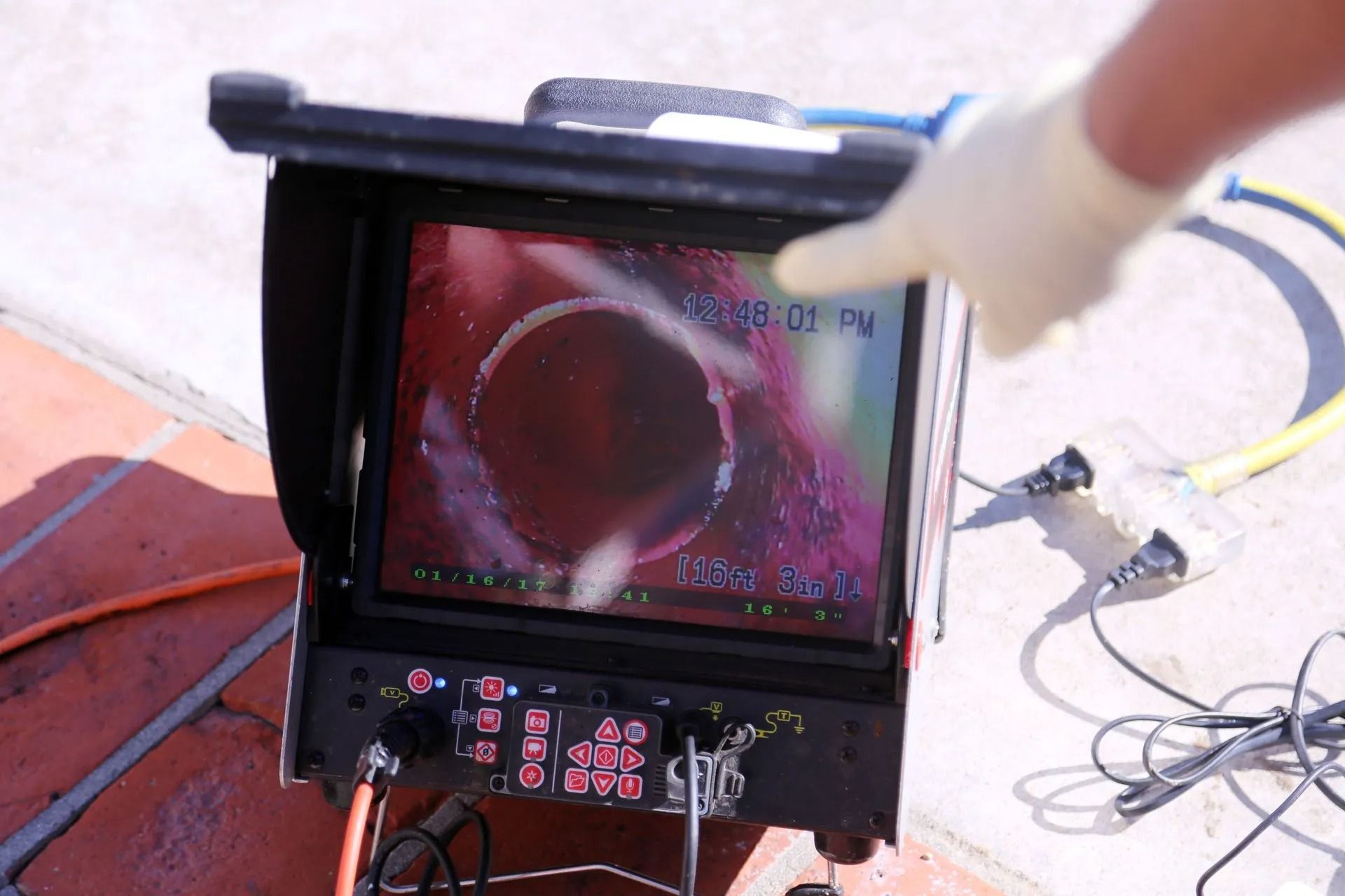 Camera monitor showing a close-up of a red circular object with a cable and tools nearby