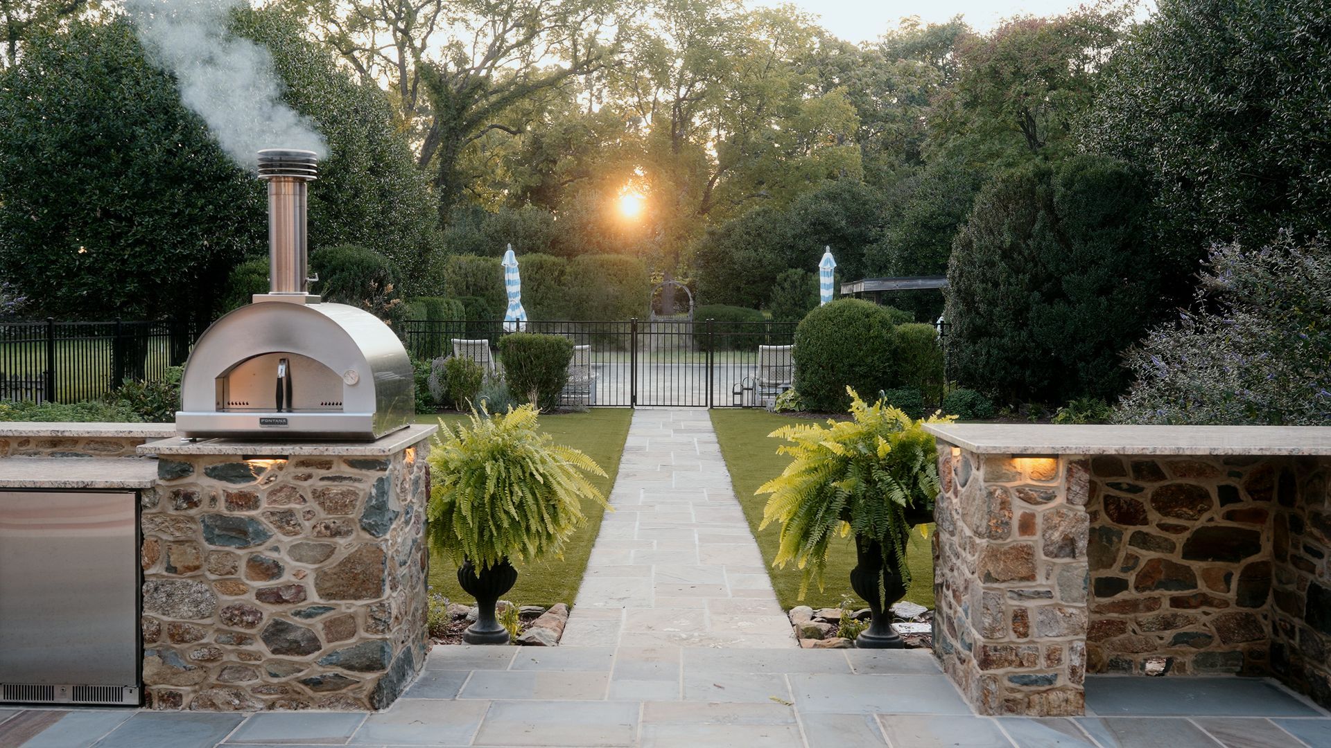 A pizza oven is sitting in the middle of a stone walkway.