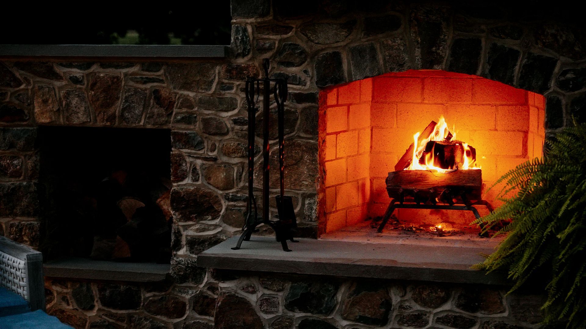 There is a fireplace in the middle of a stone wall.