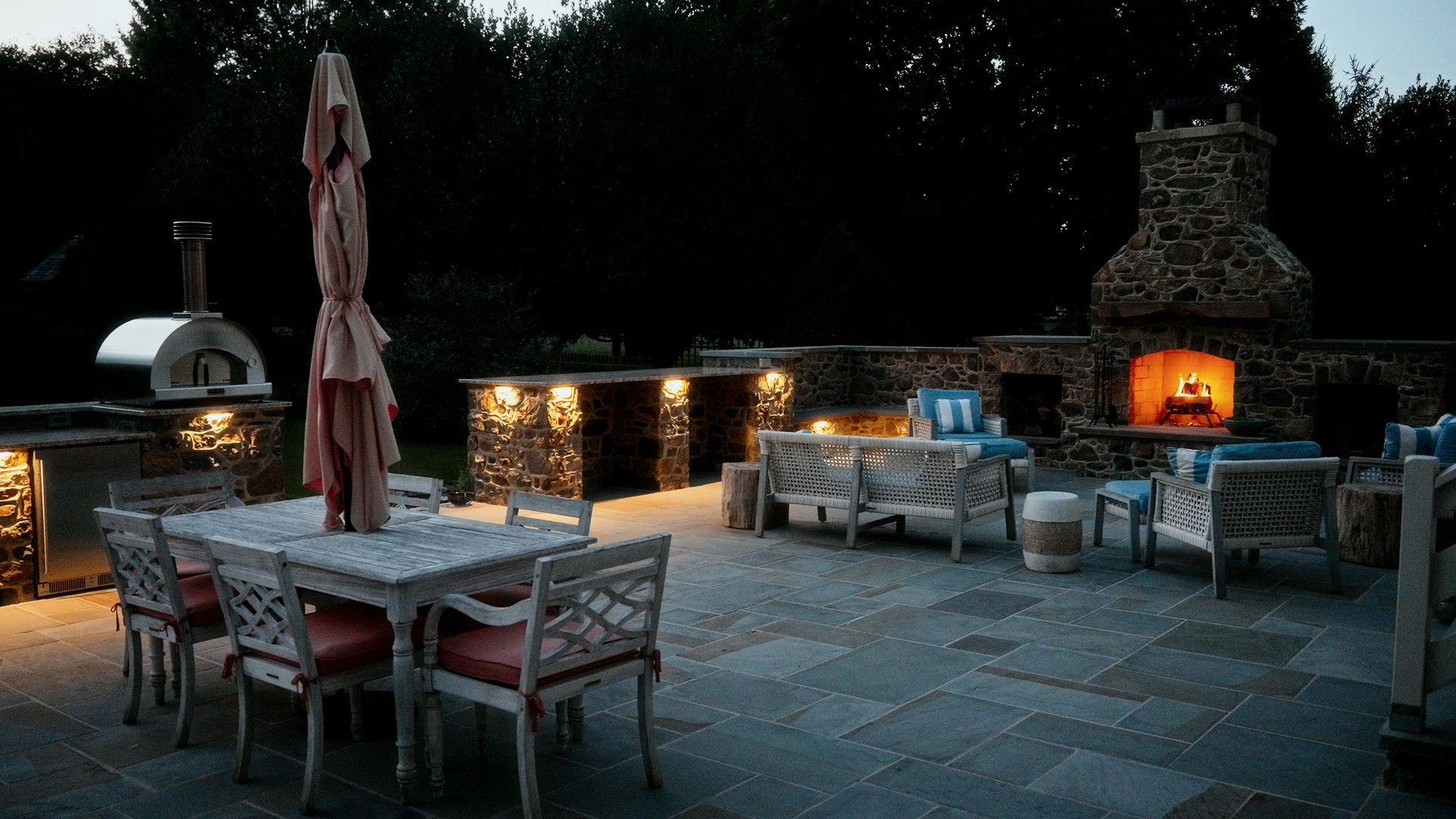 A patio with a table and chairs and a fireplace at night