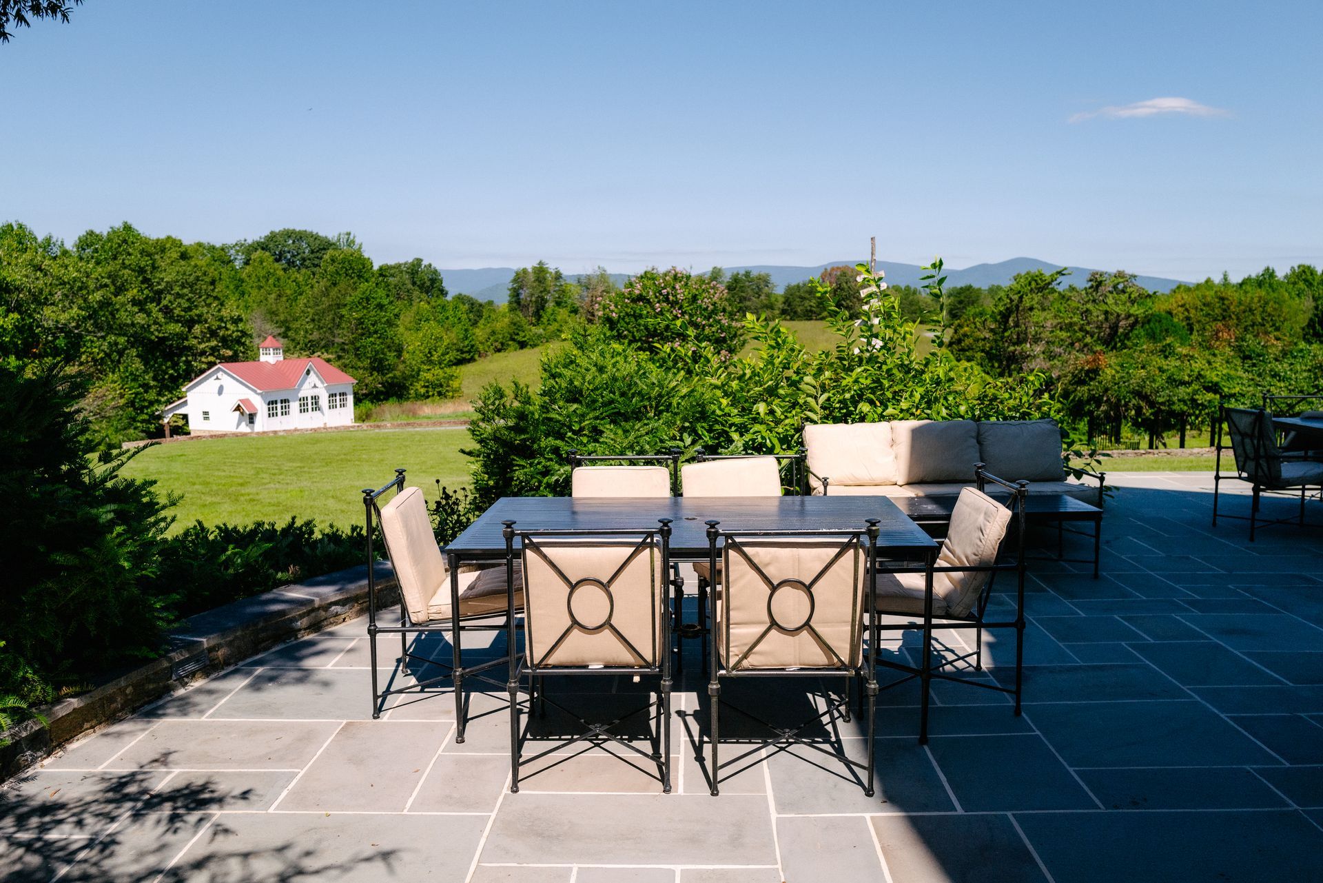 A table and chairs on a patio with a house in the background