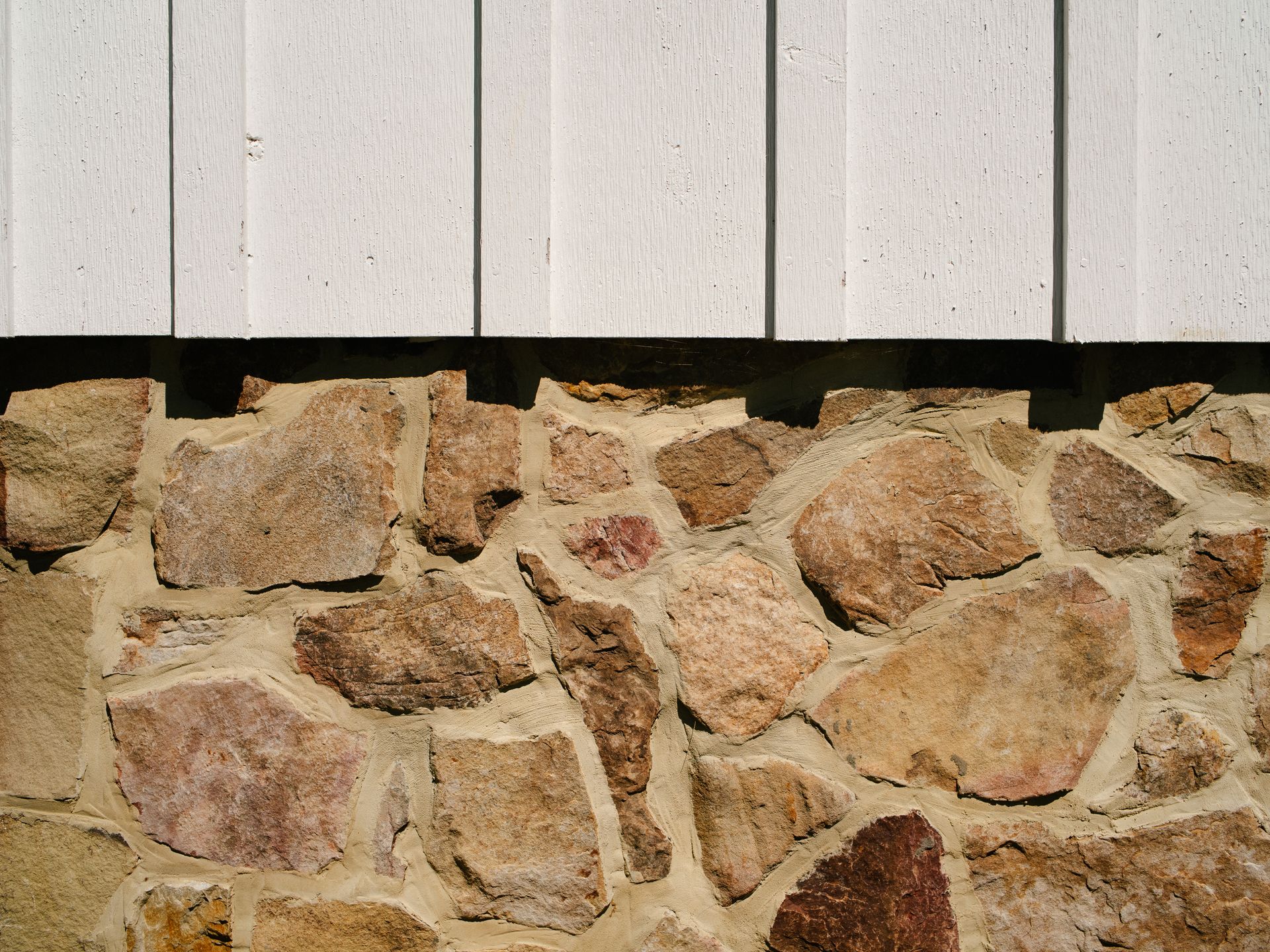 A stone wall with a white siding behind it
