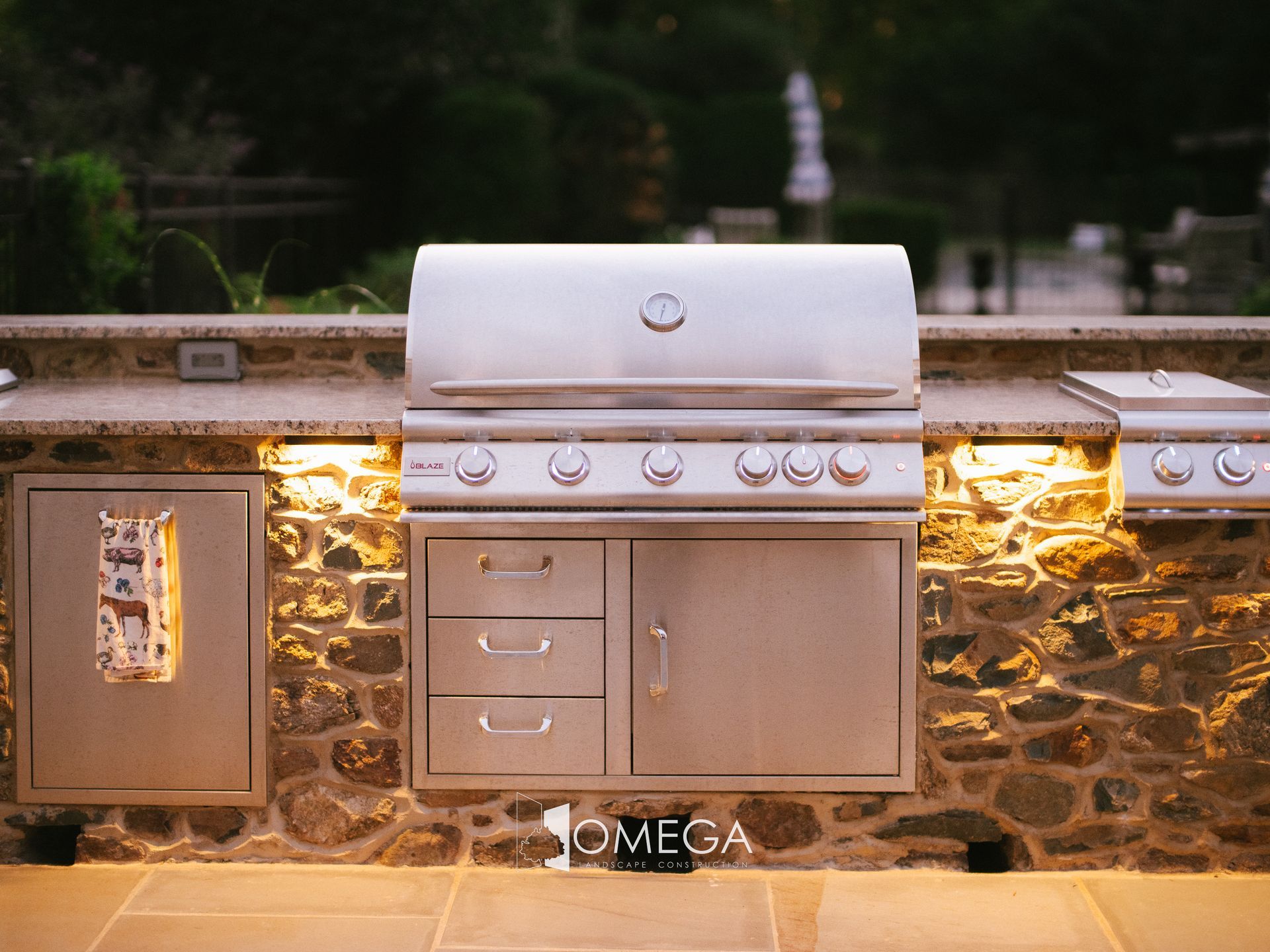 A stainless steel grill is sitting in front of a stone wall.