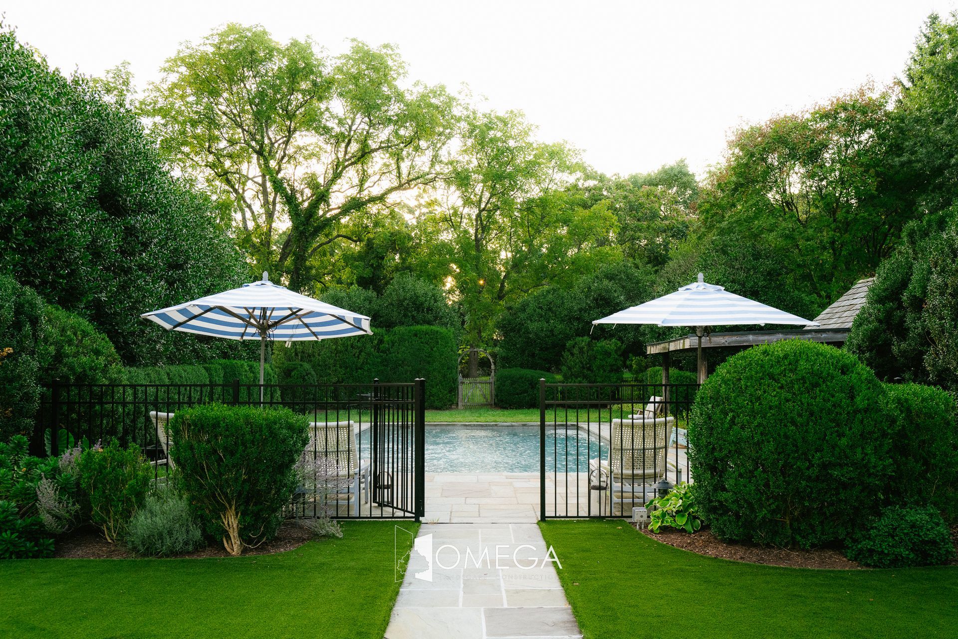 A swimming pool surrounded by trees and bushes with umbrellas