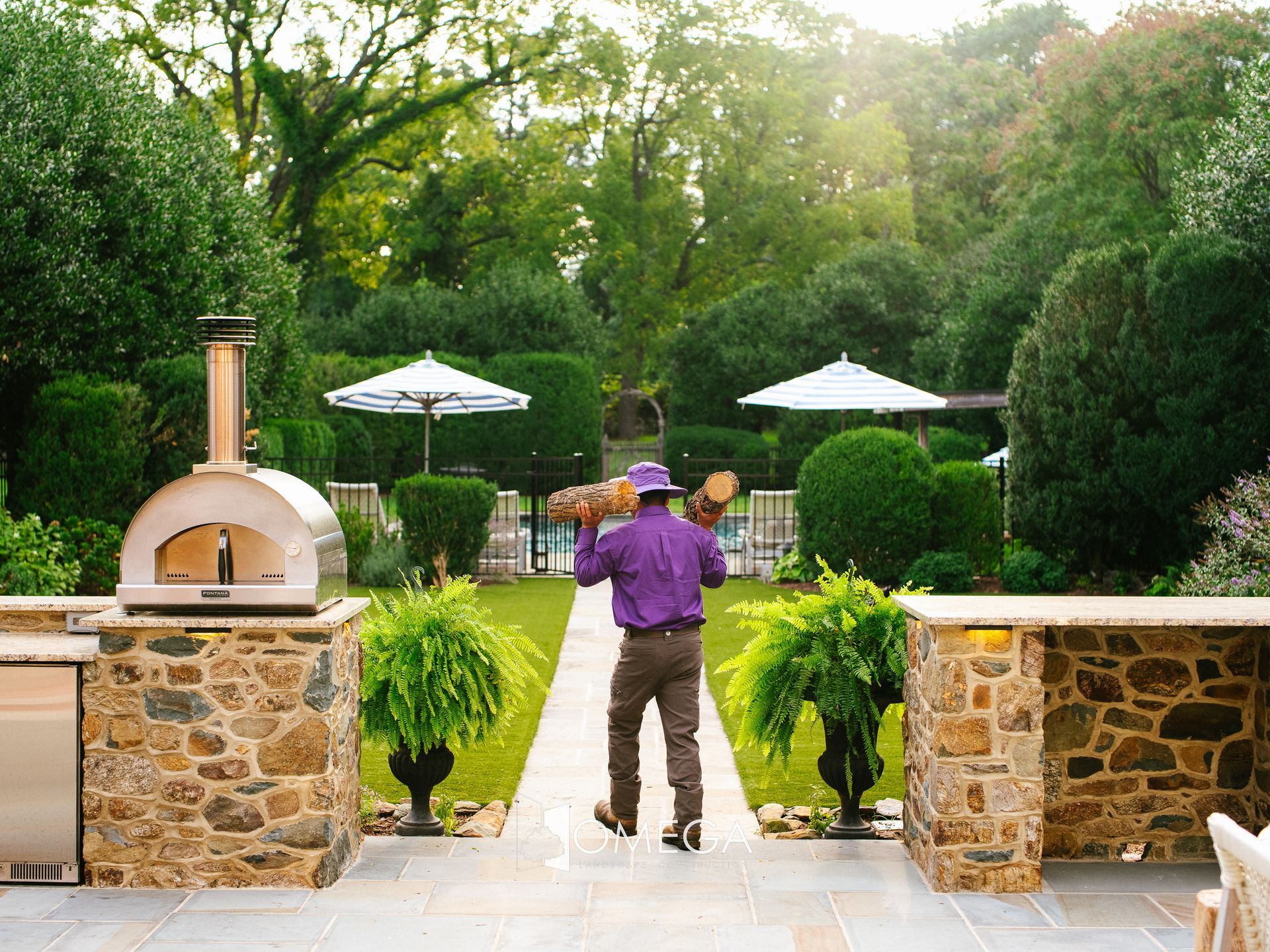 A man in a cowboy hat is walking down a path in a garden