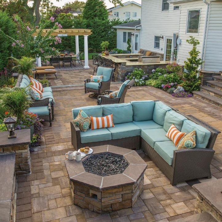 A patio with a fire pit and a sectional couch