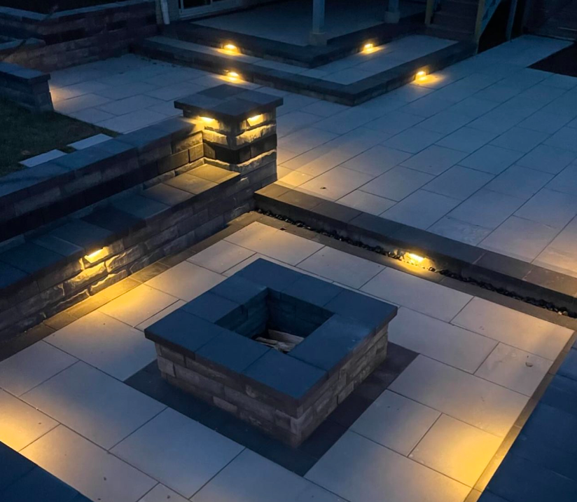 A fire pit is lit up at night on a patio.