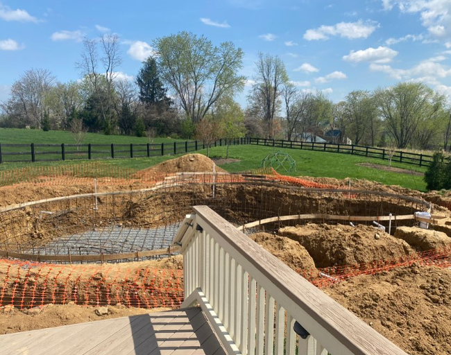 A view of a construction site from a deck with a fence in the background.