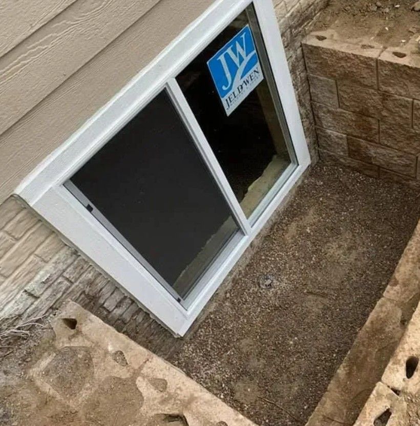 Basement window in a recessed well, surrounded by tan stone blocks.