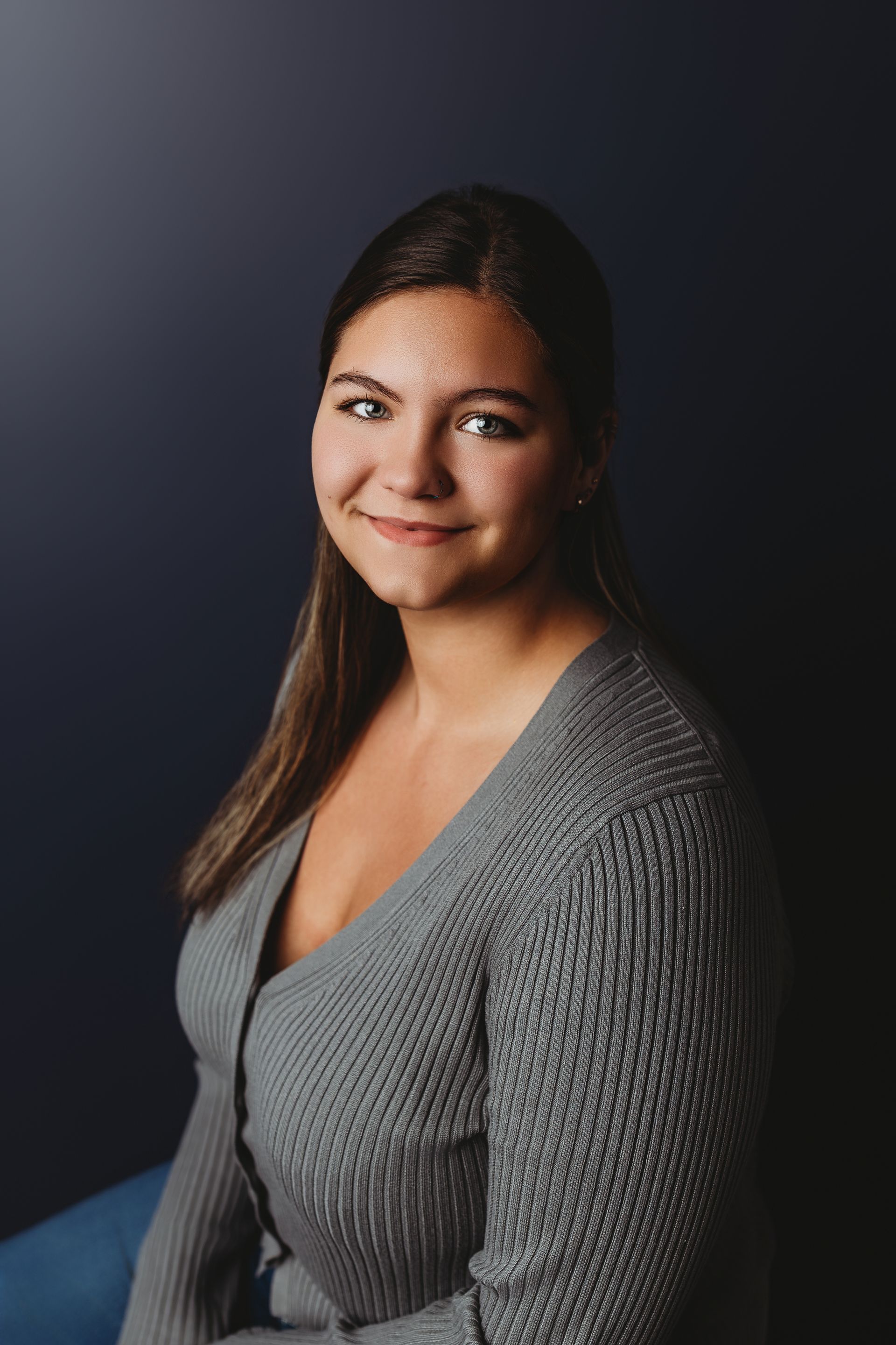 Woman with brown hair, smiling, wearing a black top, against a white background.