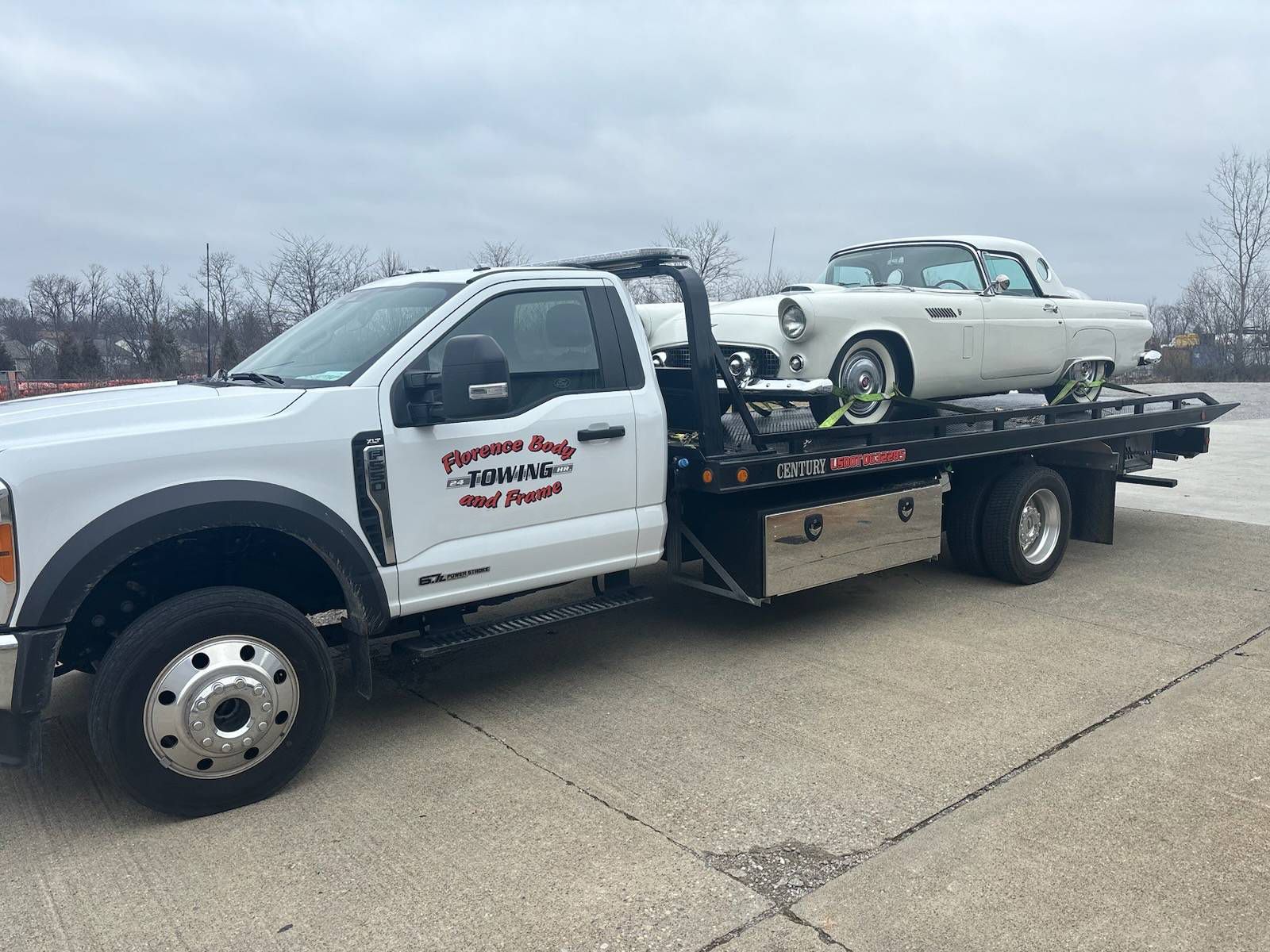 A white tow truck is towing a white car.