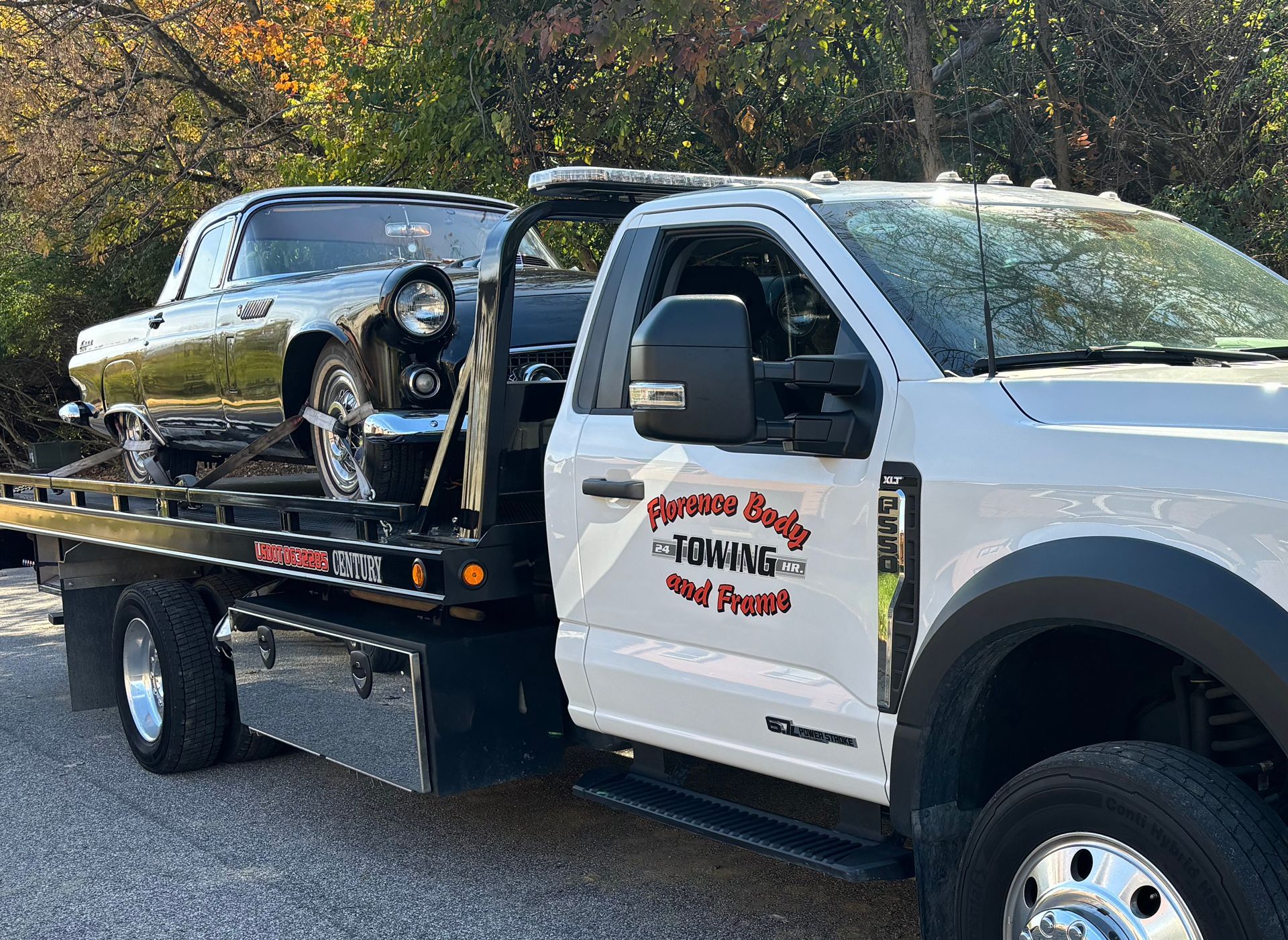 A tow truck is carrying a car on the back of it.