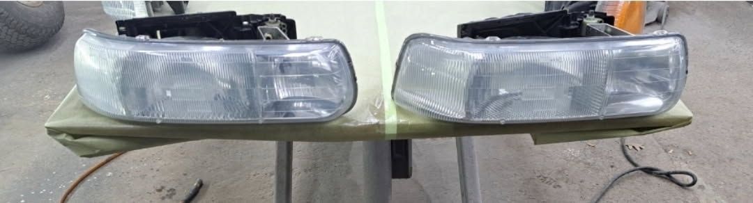 Blue pickup truck with a black camper shell and black wheels parked on a paved lot.